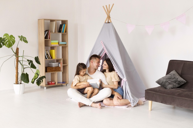 A family sits together in the living room of the house they bought